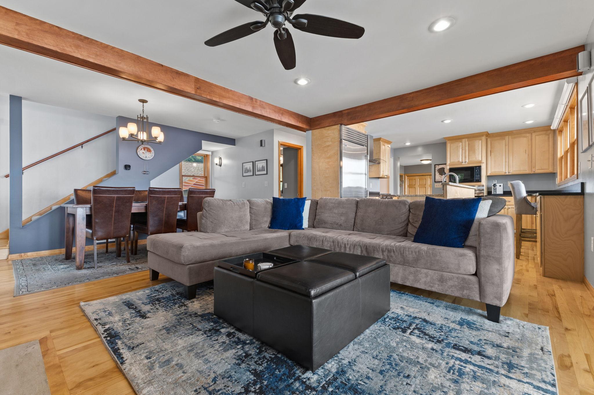 Exposed wood beams and a ceiling fan in this spacious gathering area, where the living room, dining space, and chef's kitchen come together with exceptional style and functionality.