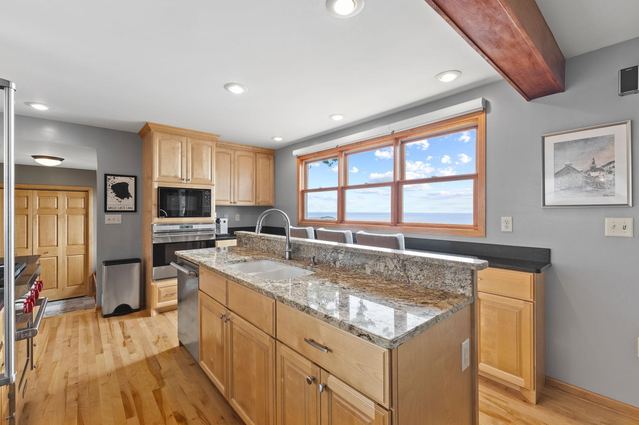 The chef's kitchen features custom maple cabinetry, honed granite countertops, a spacious center island, and stunning lake views designed for everyday living and entertaining.