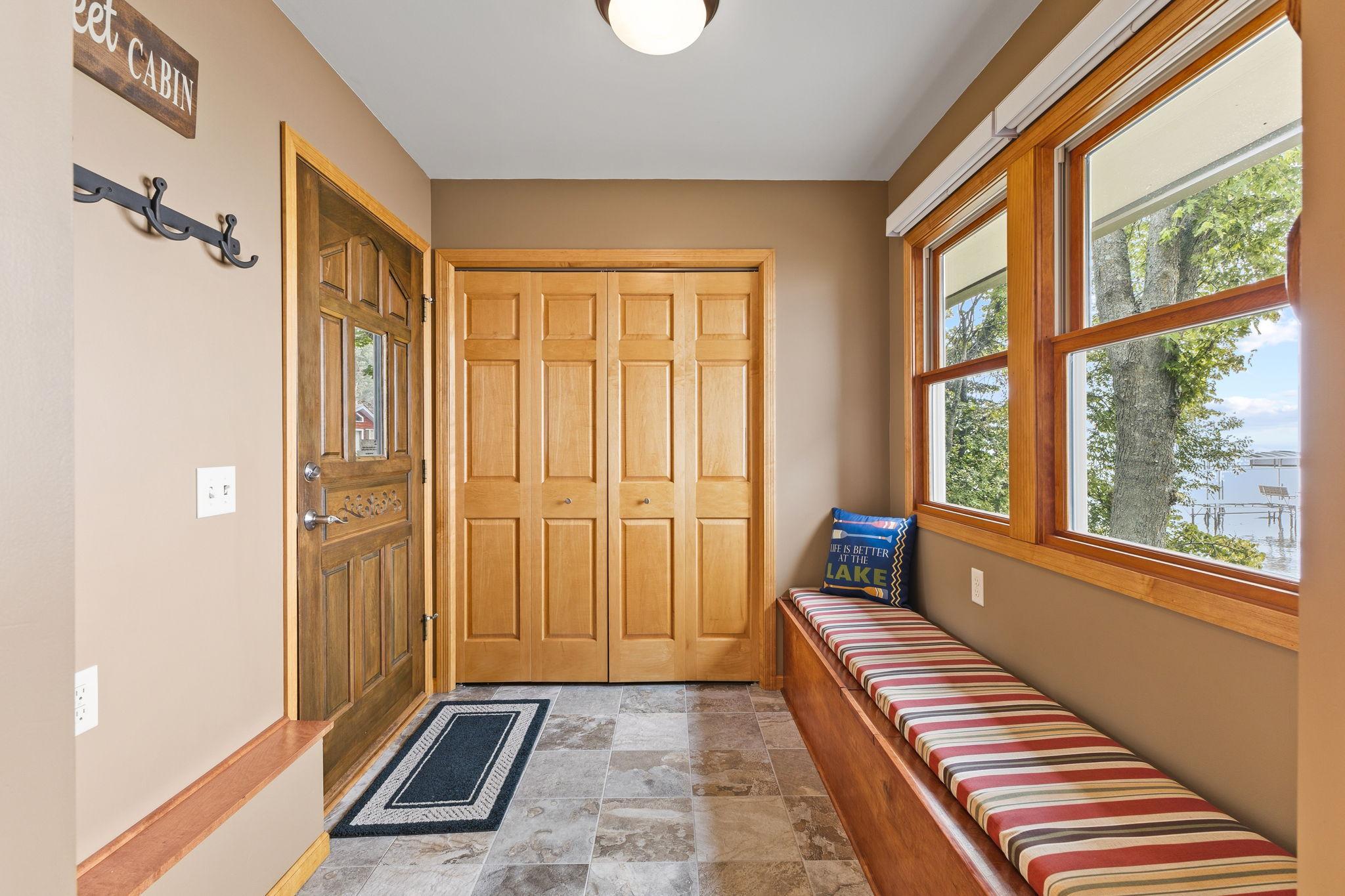 Guests are welcomed by a thoughtfully designed entry featuring natural woodwork, a built-in window seat, abundant storage, and serene views of the lake.