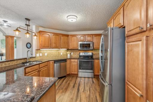 LVP flooring, granite counters, stainless-steel appliances, tiled backsplash, under cabinet lighting.