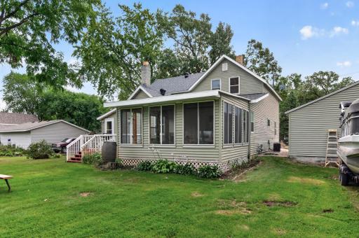 Rear view highlights the home's three-season porch and expansive yard beyond.