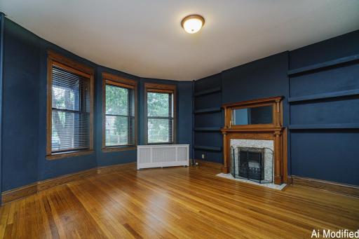 The family room opens to the front of the building, and features bay windows, a fireplace with a period mirror, floating shelves, and a smooth ceiling.