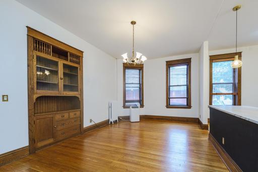 The dining room has striking hardwood floors and large windows, and opens to a beautiful built-in hutch with glass doors.