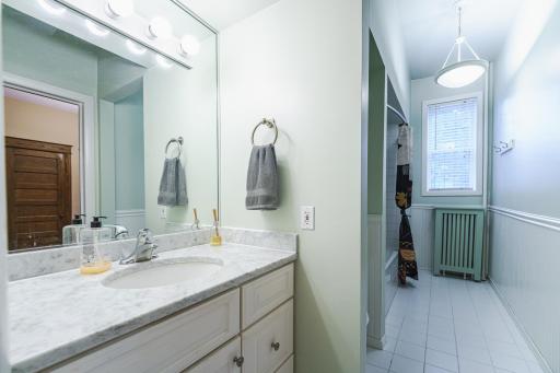 The FULL bathroom is light and bright, with a window, tile flooring, white vanity and wainscoting, and a marble countertop. It has a jetted tub and a closet.