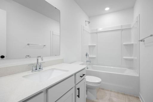 Situated near the secondary bedrooms, this full-sized bathroom comes well-equipped with a quartz-topped vanity and a combination shower and tub to maximize the interior space.