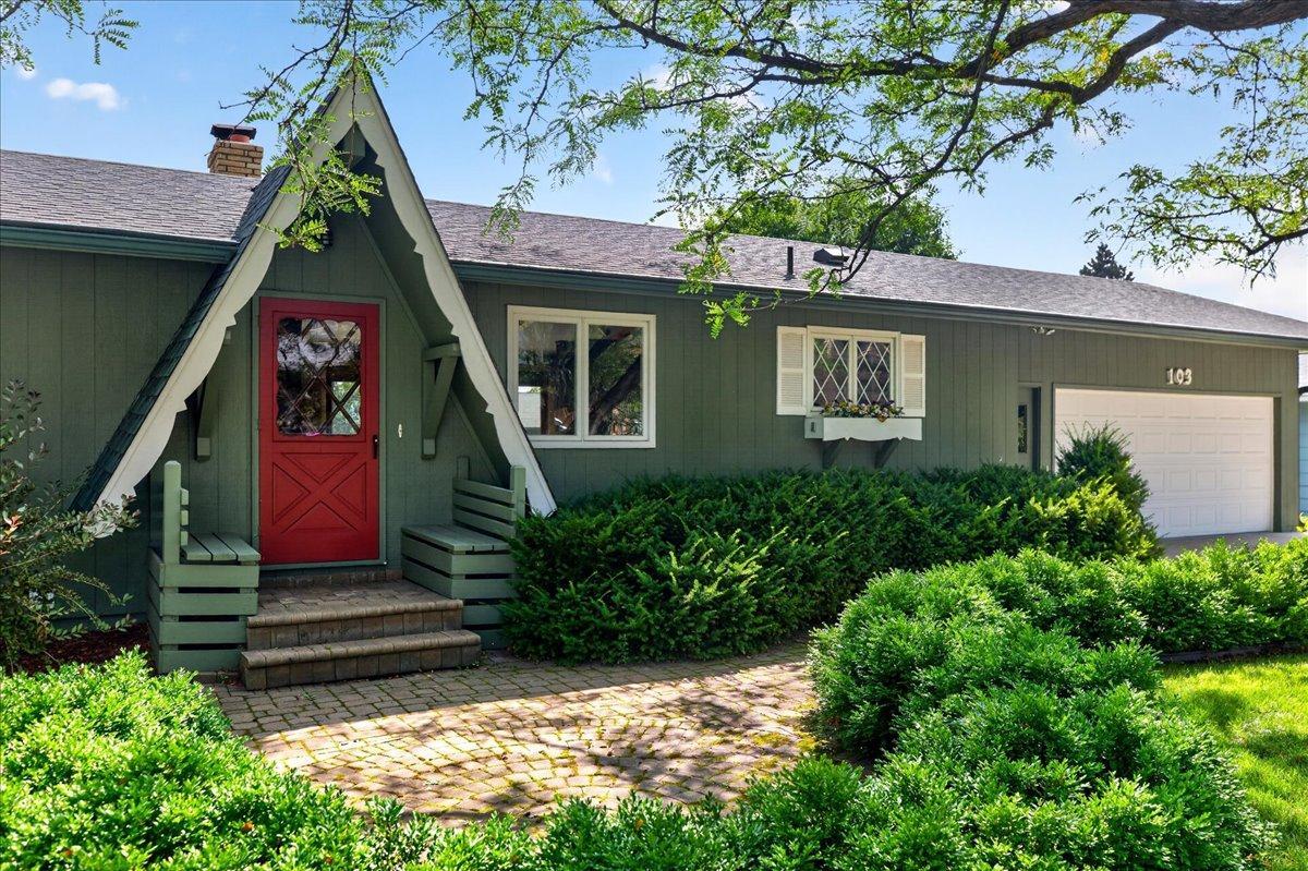 Inviting paver stone front walk with patio space defined by a lush boxwood hedge.