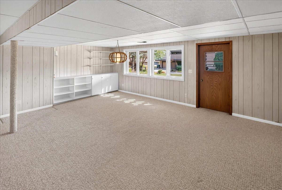 Lower level family room offers built-in cabinetry/bookcases and hanging light fixture.