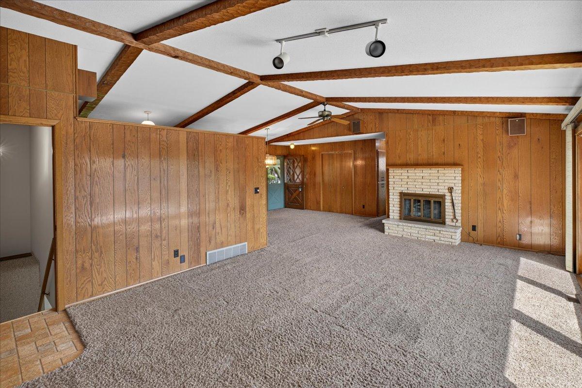 Spacious living room features track lighting and vintage fireplace.