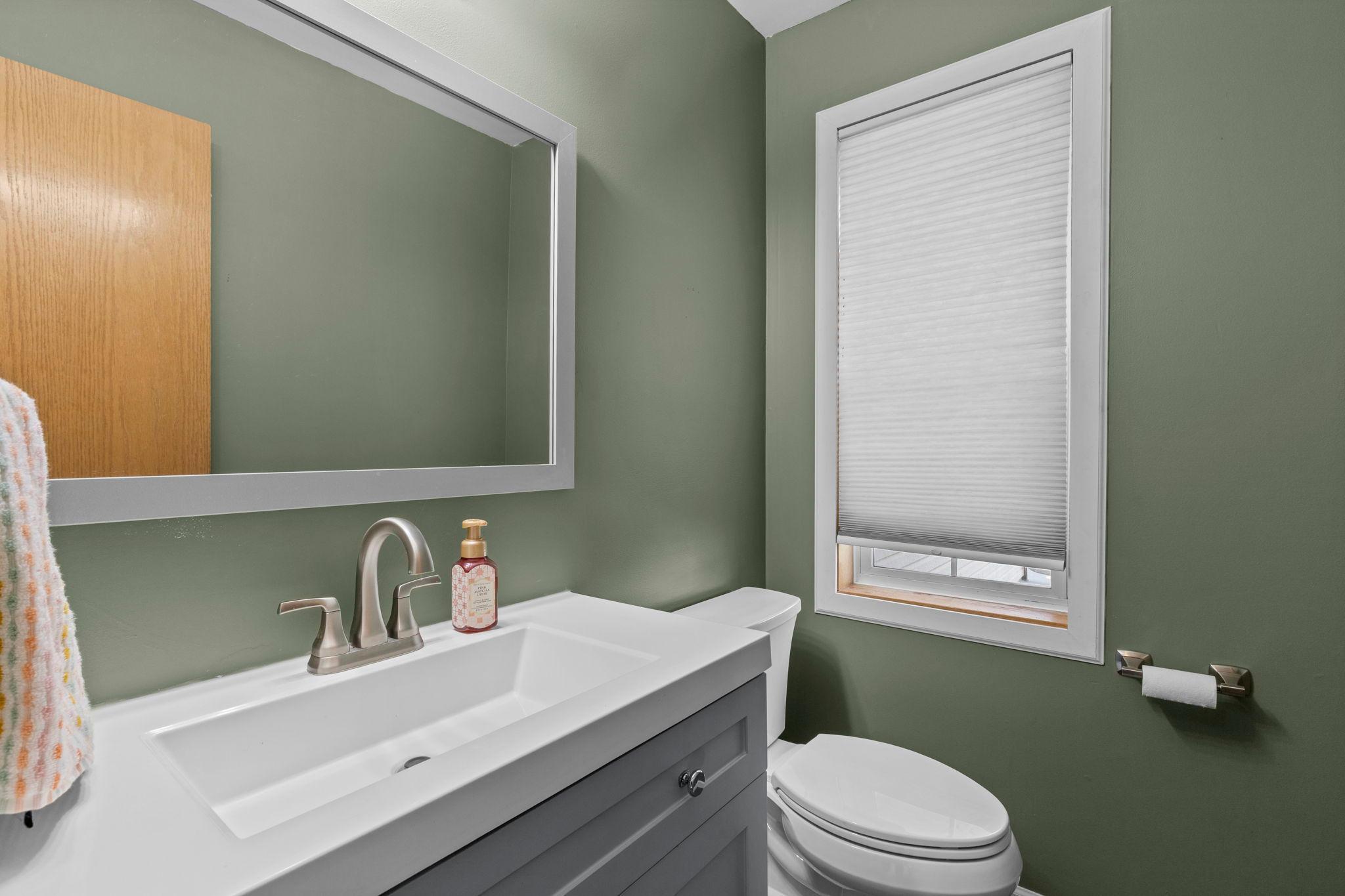 The updated main-floor half bath features a fresh, modern vanity and is conveniently located for guests
