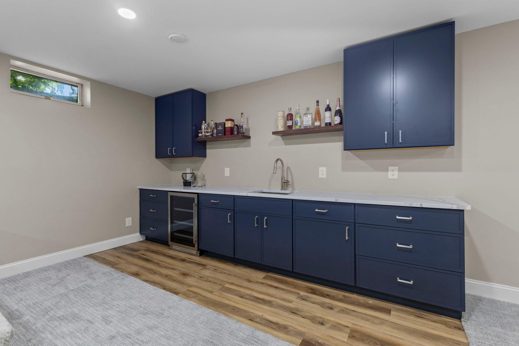 A fantastic lower-level wet bar with rich cabinetry, beverage refrigerator, sink, and plenty of storage—perfect for entertaining