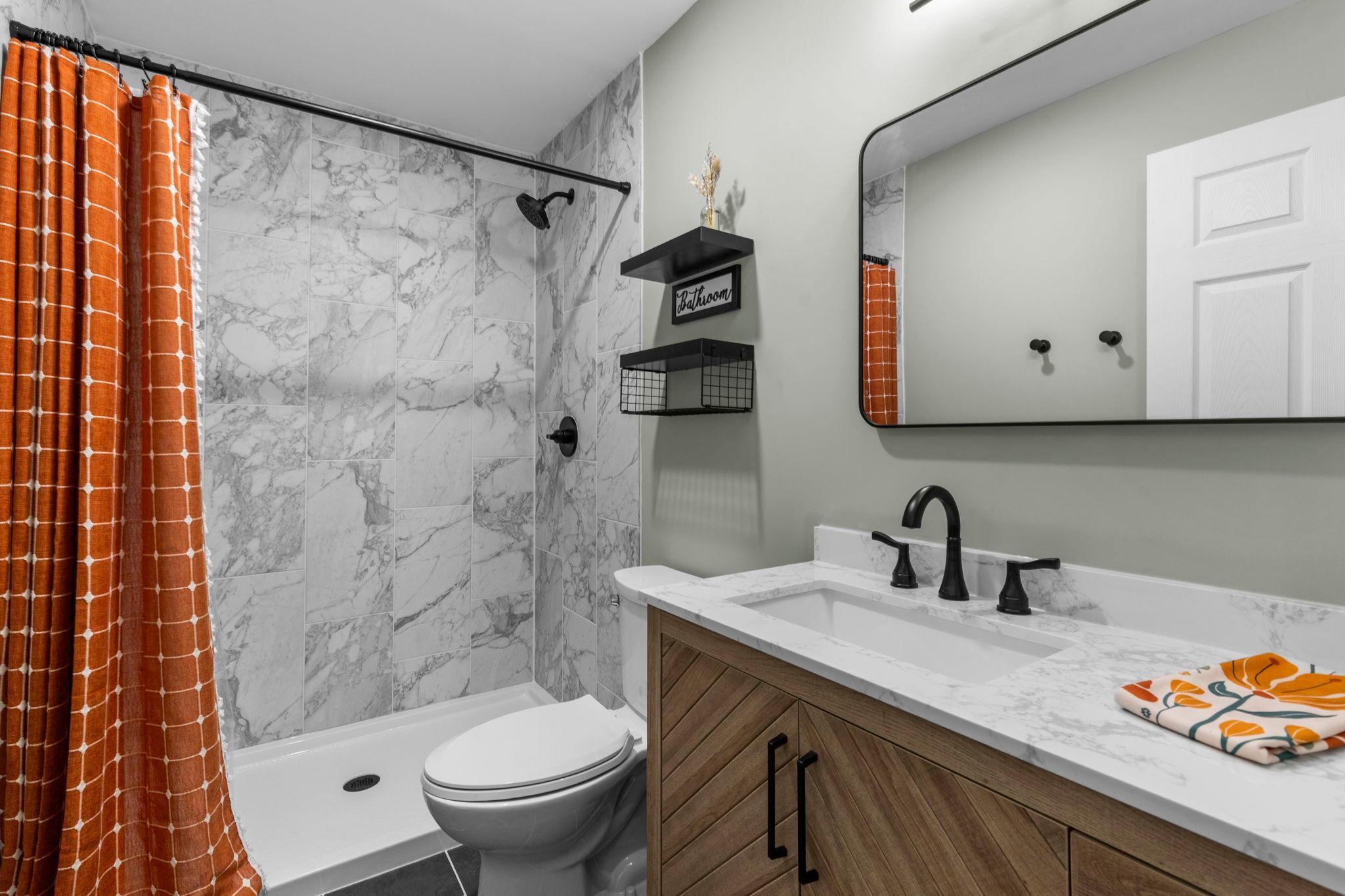 The lower-level bath features a beautiful tiled shower, updated vanity, and stylish finishes