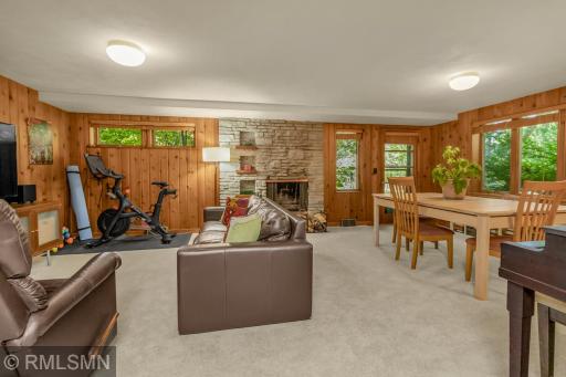 The paneling, stone fireplace, and evergreen views give this space a cozy, up north, cabin feel.