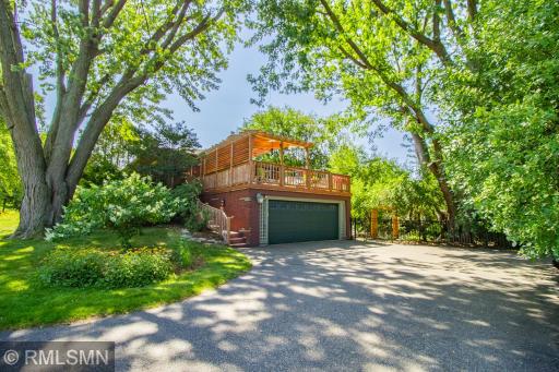 View of the back of the home. Two car garage and large paved driveway with extra parking spaces.
