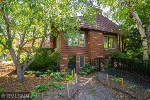 The west side of home, which shows the walkout from the basement level. Gorgeous brick and stonework! The beautiful black metal fencing was installed in 2022 and fully encloses the back yard.