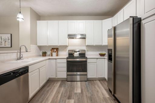 The beautifully refreshed kitchen offers crisp white cabinetry, stainless steel appliances, ample workspace, and plenty of storage.