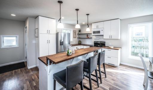 The kitchen with newer cabinets, countertops, plumbing, breakfast bar, and more