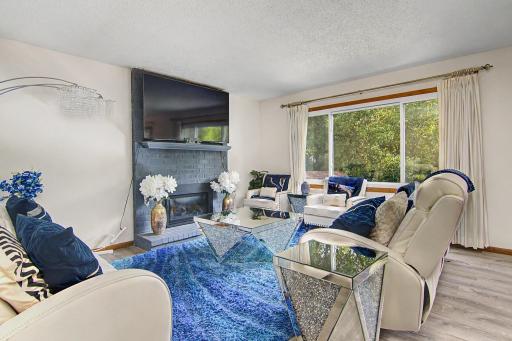Bright main-level living room featuring a fireplace and large picture window.