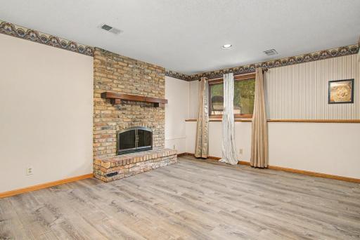 Lower-level family room featuring a beautiful brick fireplace and updated flooring.