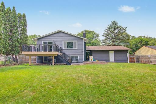 Rear exterior view showcasing the deck, additional patio space, and expansive yard. Freshly Painted Deck.