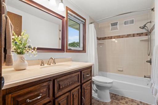The upper-level full bath serves the additional bedrooms with a tub/shower combo and warm wood vanity.