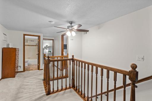 The upper-level landing connects to the additional bedrooms and full bath, with an open rail overlooking the stairs below.