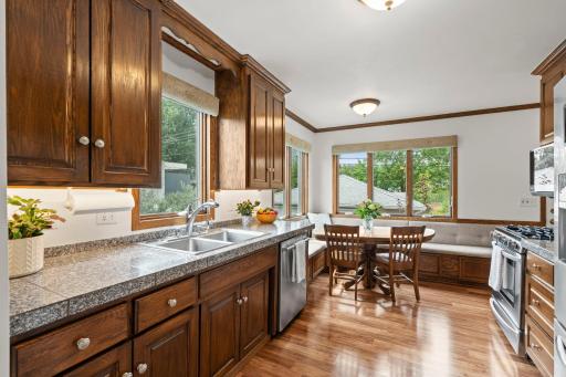 A wider view of the kitchen showcases granite countertops, a gas range, and abundant cabinet storage.