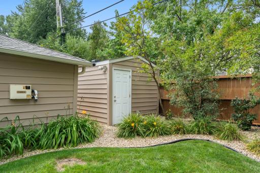 The detached garage's rear workshop entrance opens to landscaped side beds along the fence line.