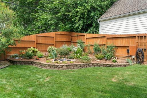 The fully fenced backyard is beautifully landscaped with mature perennial garden beds.