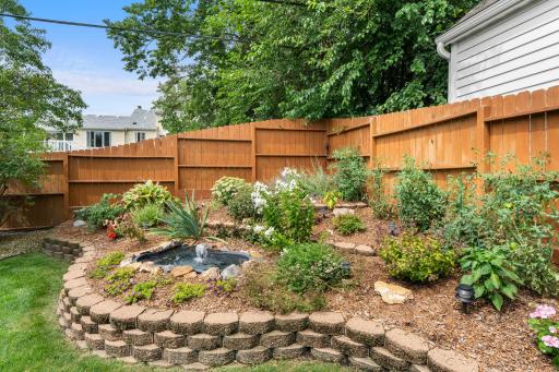 A charming garden fountain and lush plantings add a tranquil touch to the fully fenced backyard.