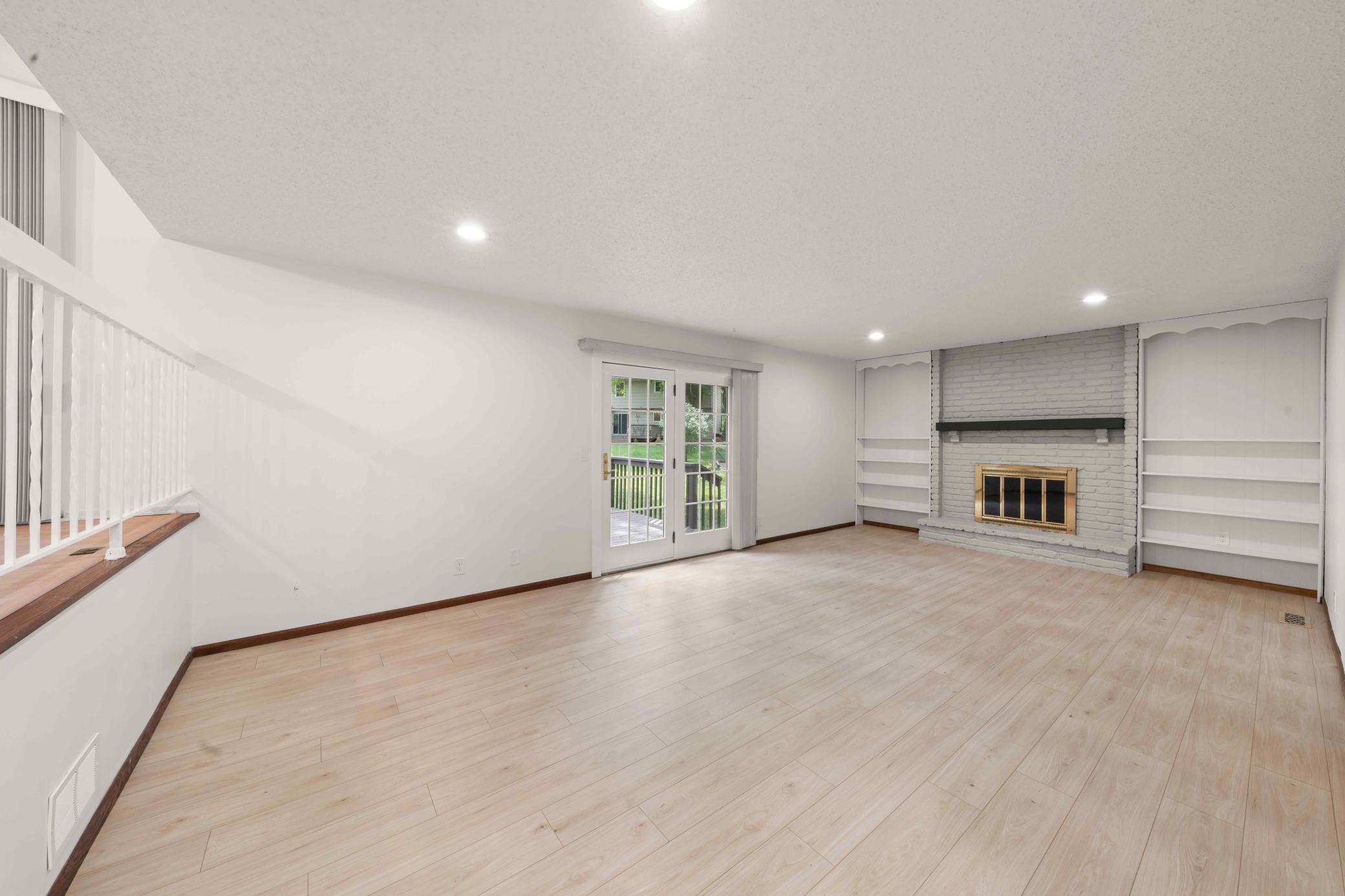 Spacious family room centered around a brick fireplace with built-in shelving and backyard access