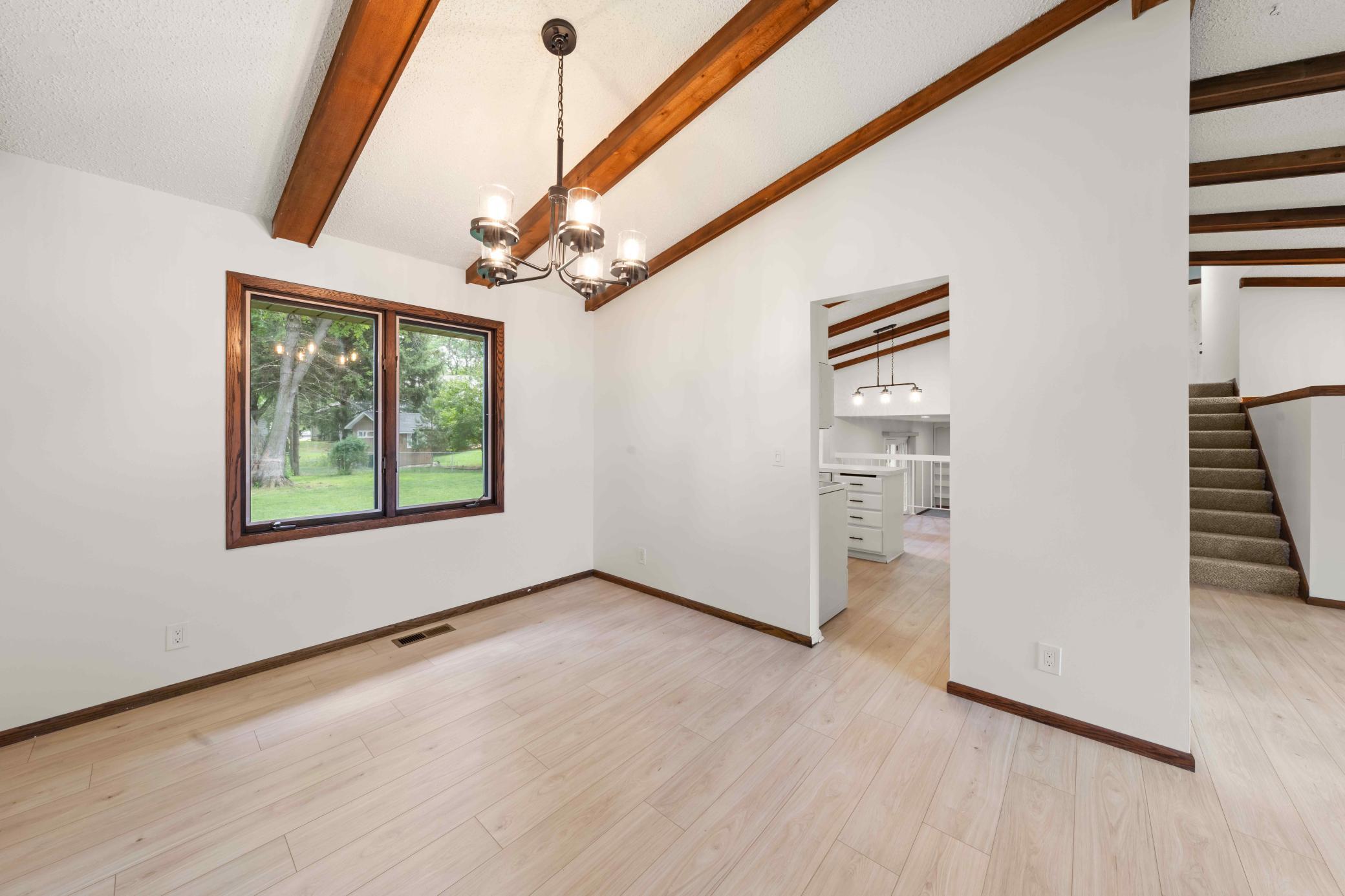 Light-filled formal dining room with vaulted, beamed ceiling and views of the backyard