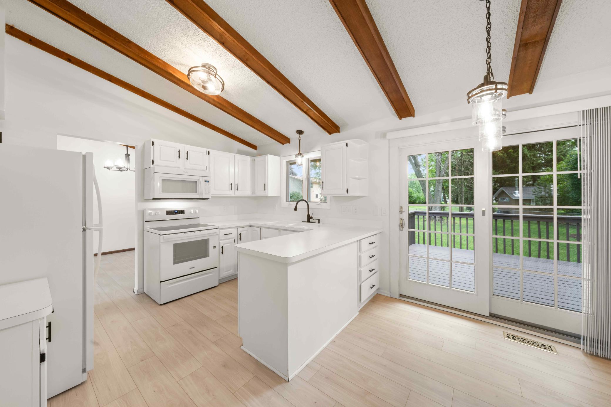 Inviting kitchen and casual dining area with vaulted beams and direct access to the deck