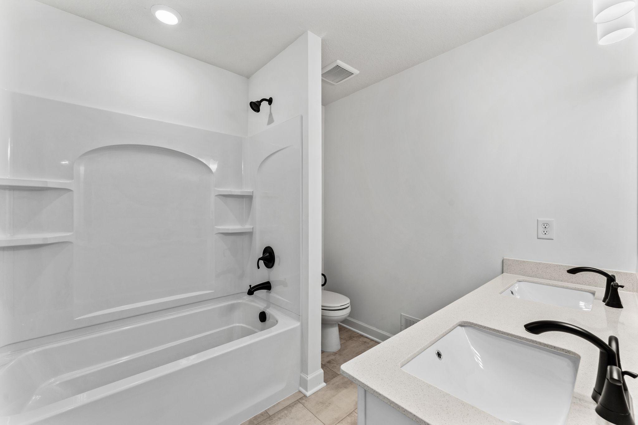 This shared full bathroom includes a full-width vanity mirror and a shower-tub combination.
