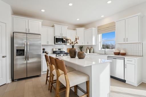 (Photo is of an inventory home, actual homes finishes will vary) The spacious kitchen features a large center island, quartz countertops, LVP floors, stainless steel appliances, and more!