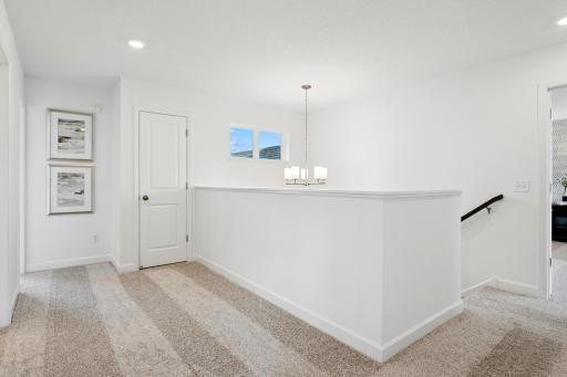 (Photo is of a decorated model, actual homes finishes will vary) Upper level hallway! Spacious and accented with two windows allowing wonderful natural light to shine through.