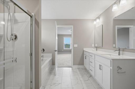 Primary bathroom featuring double sink vanity, a separate soaking tub and shower.