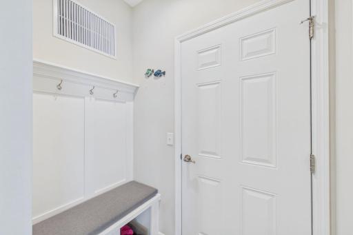 Door leading to garage with custom bench and coat hooks.