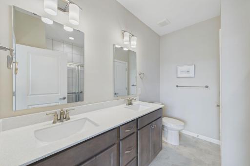 Primary bathroom with dual vanities, solid surfaced counter, upgraded cabinetry.
