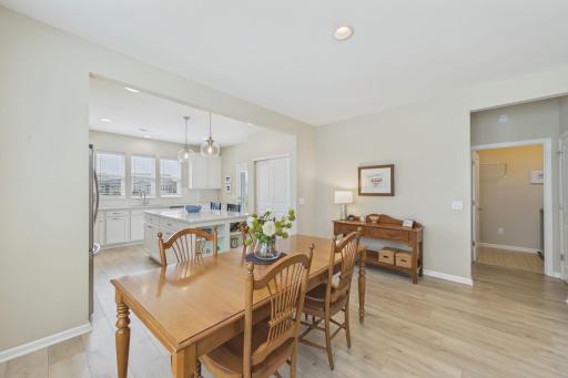 Dining area neighboring open concept living room & kitchen, neutral decor, upgraded flooring & window treatments.