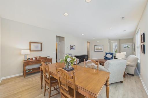 Dining area neighboring open concept living room & kitchen, neutral decor, upgraded flooring & window treatments.