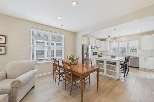 Dining area neighboring open concept living room & kitchen, neutral decor, upgraded flooring.