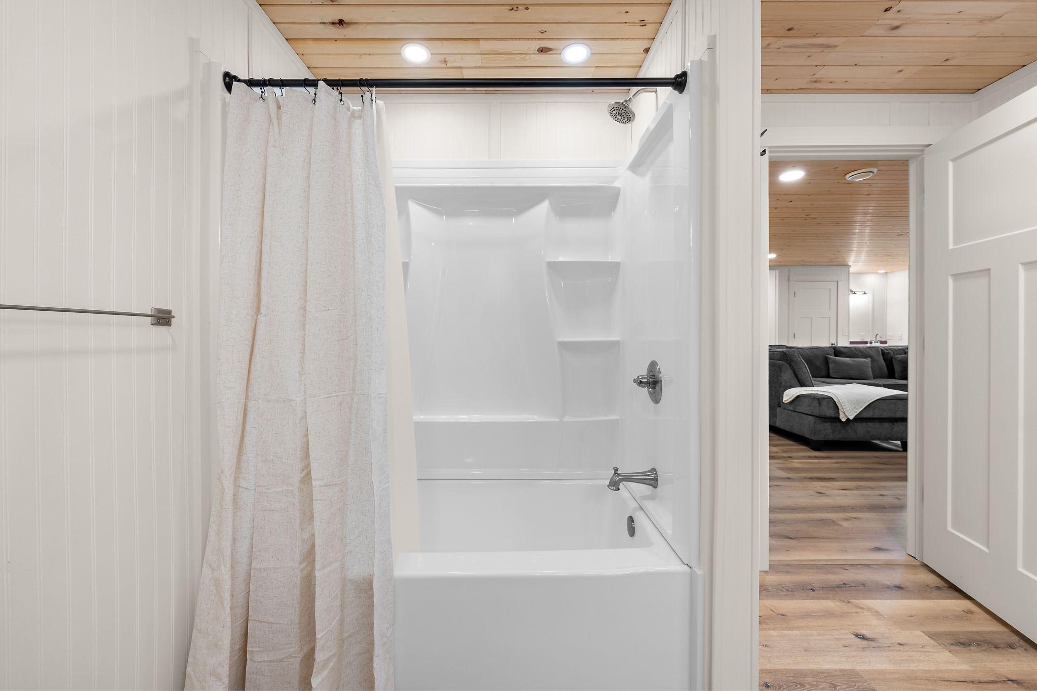 The lower level full bathroom has a tub/shower combo. The lower level family room is visible through the open door on the right.