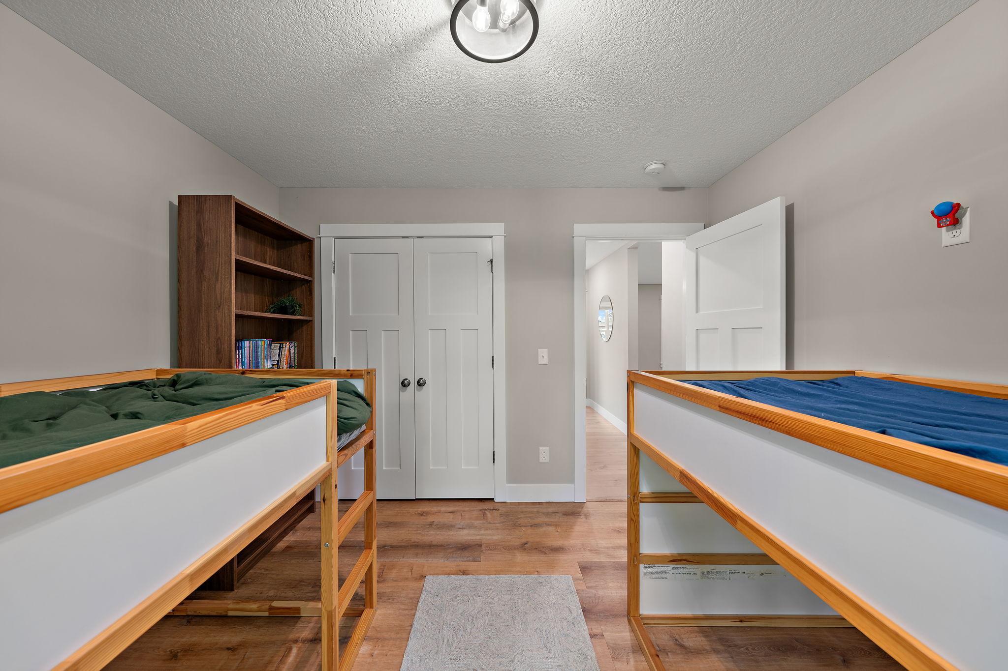 The third main floor bedroom with closets to the left and the main floor hallway seen through the open door on the right.
