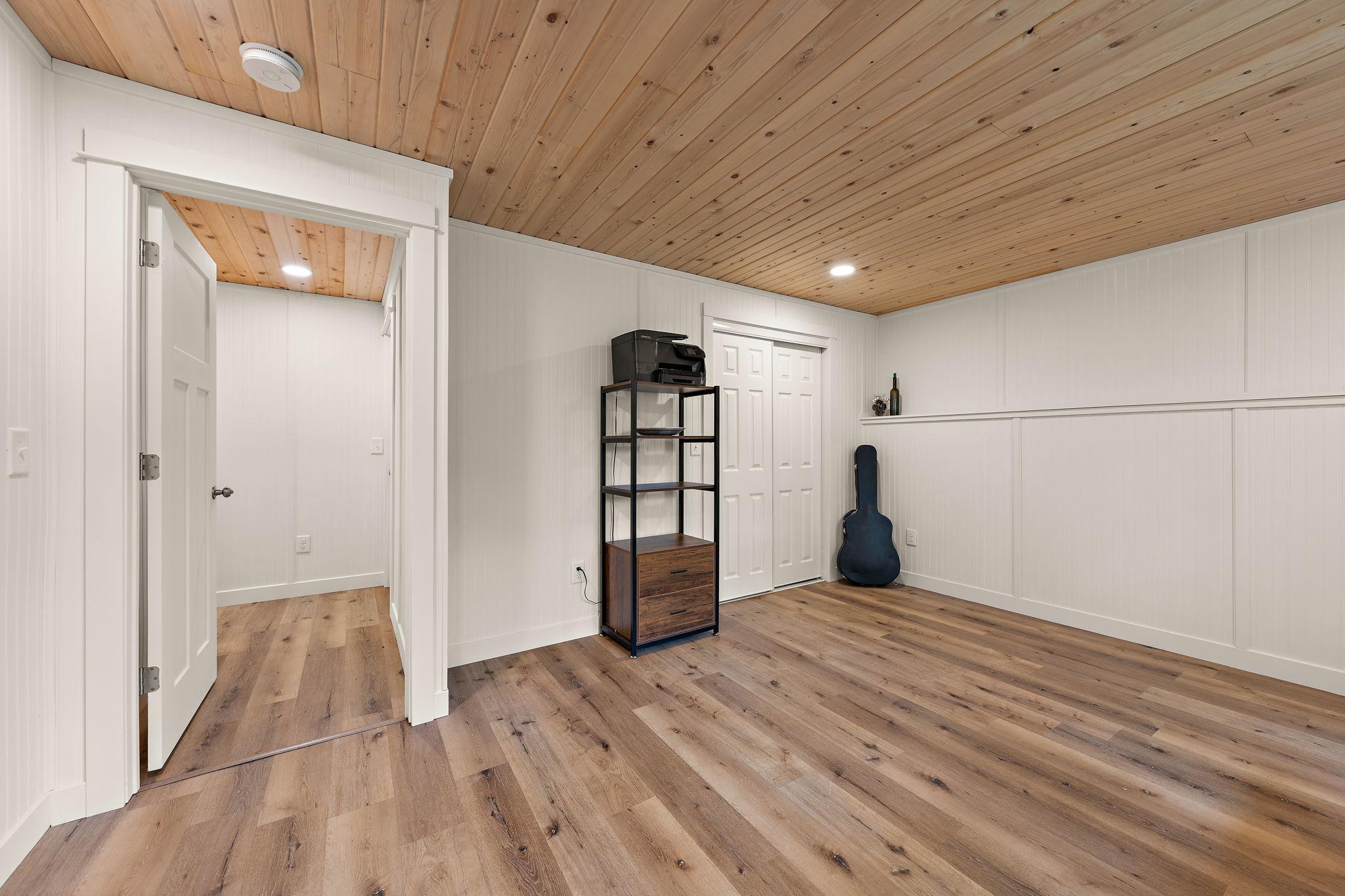 The fourth bedroom in the lower level with the door leading to the hallway and family room open on the left and closet on the right.
