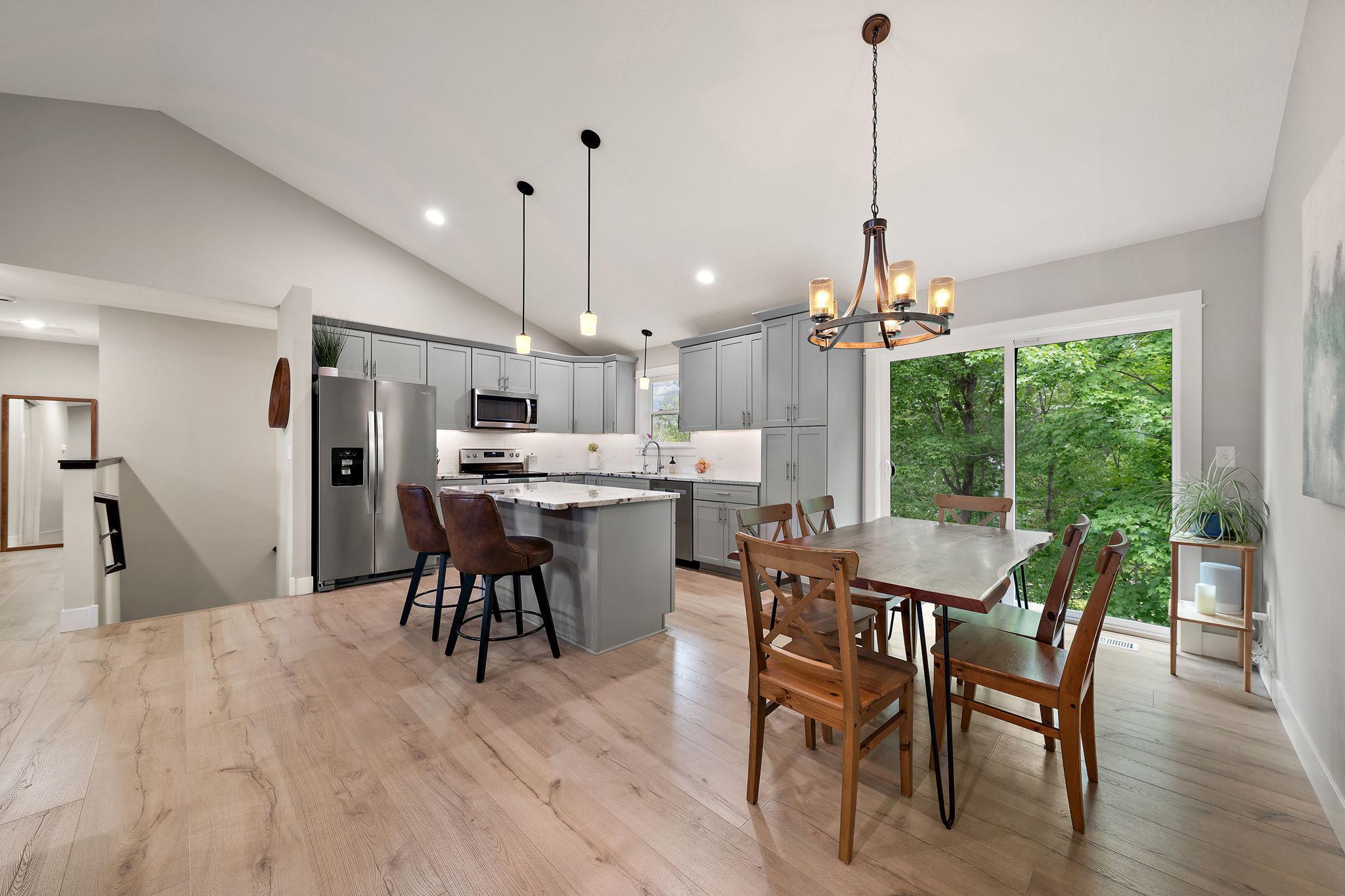 The kitchen and dining area feature hardwood floors and a open concept layout. The stair leading to the lower level are seen to the left of the refrigerator.