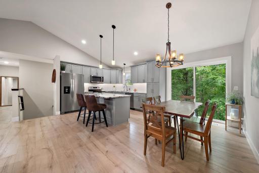 The kitchen and dining area feature hardwood floors and a open concept layout. The stair leading to the lower level are seen to the left of the refrigerator.