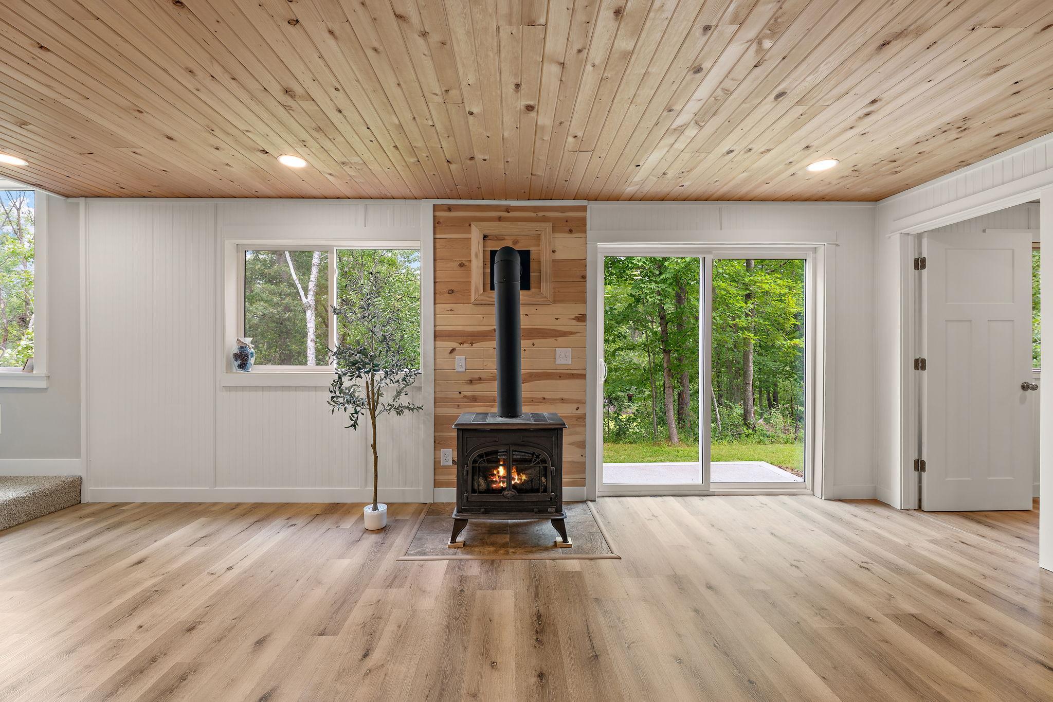 The freestanding gas stove is a cozy addition to the lower level to chase away the chill of cool nights. The walkout basement leads out to the backyard. The fifth bedroom is through the open door on the right.