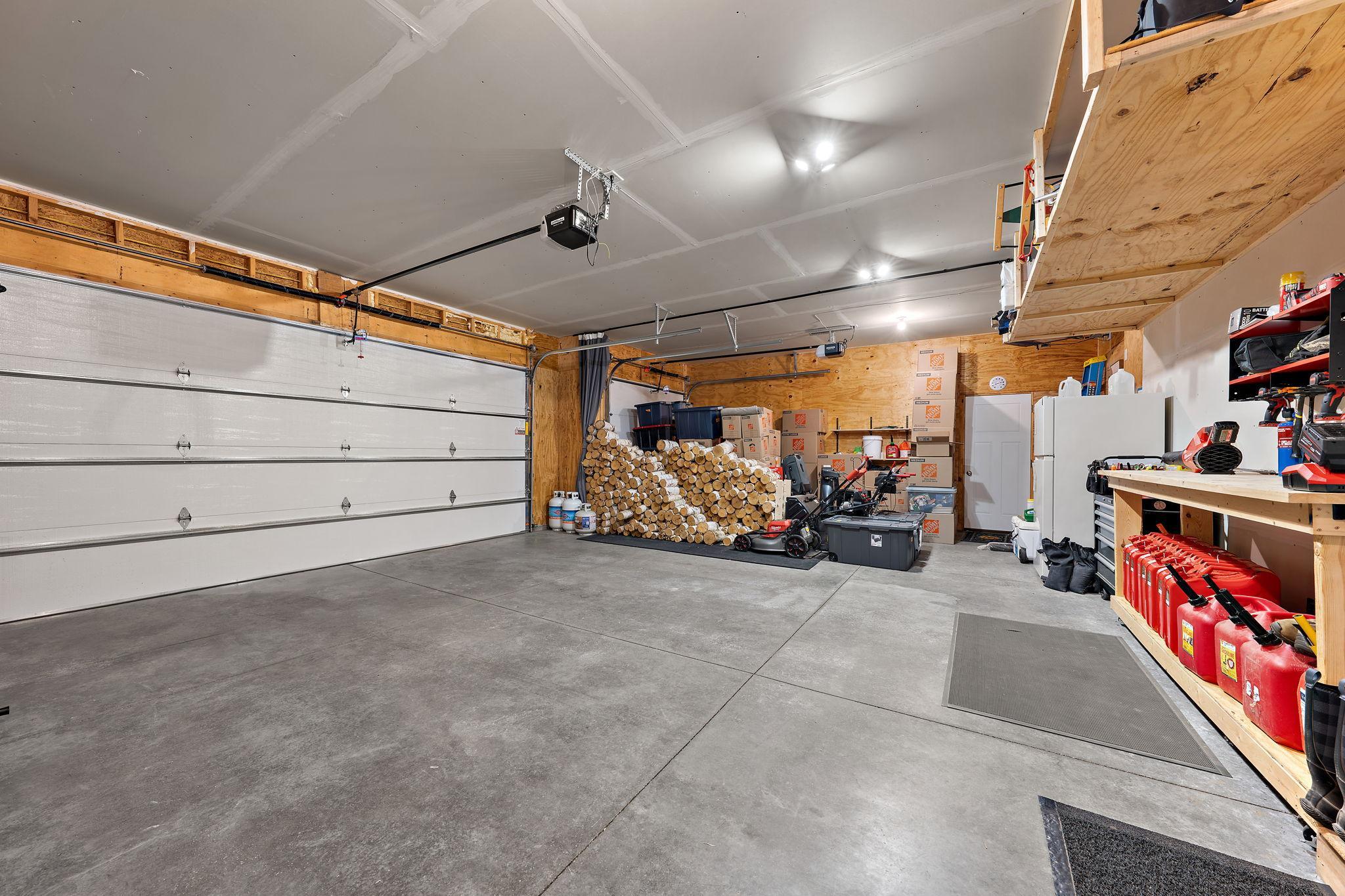 The garage is a three stall and has a workbench and storage shelves. The garage also has wood look insulated doors.