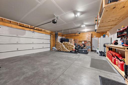 The garage is a three stall and has a workbench and storage shelves. The garage also has wood look insulated doors.