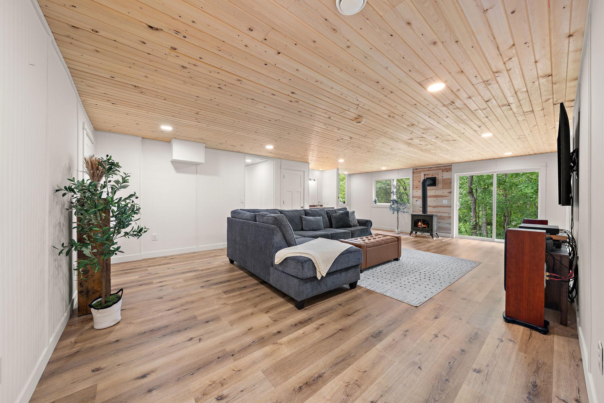A view of the family room from the full lower level bathroom. The fifth bedroom is on the far right to the right of the patio doors and the hallway with utility room and fourth bedroom is beyond the couch.